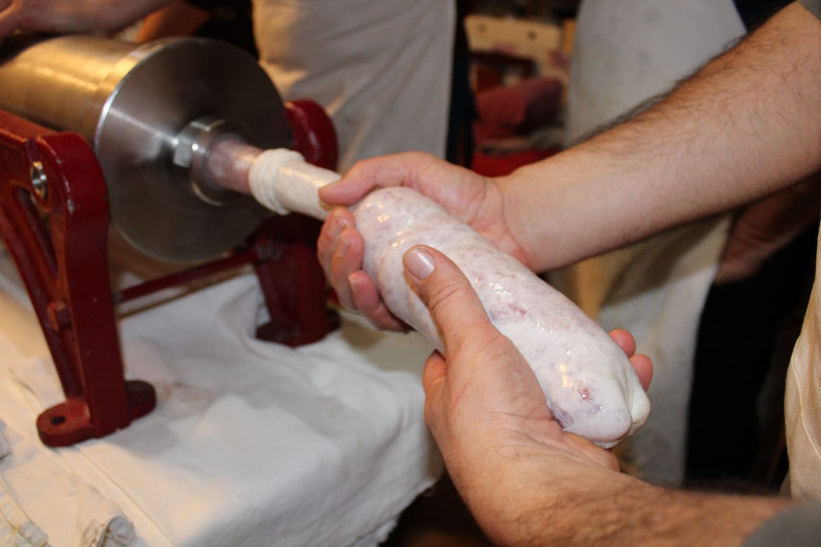 Hands holding fresh sausage coming off a stuffing machine
